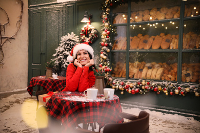 Photo of Beautiful woman at table in decorated cafe. Christmas celebration