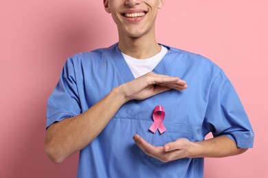 Mammologist with pink ribbon on color background, closeup. Breast cancer awareness