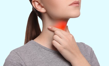 Endocrine system. Woman doing thyroid self examination on light blue background, closeup