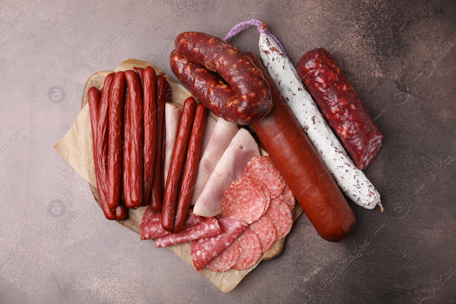 Photo of Different types of sausages on brown table, flat lay