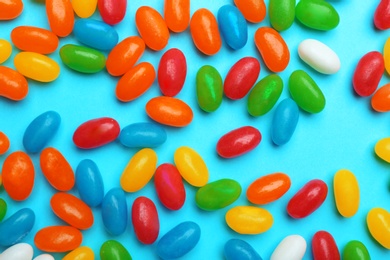 Photo of Tasty colorful jelly beans on blue background, flat lay