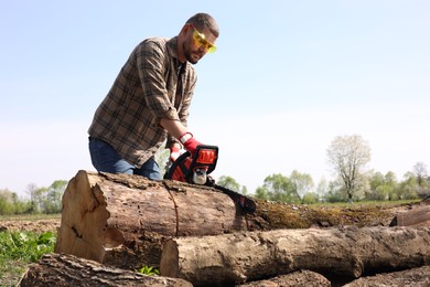 Man sawing wooden log on sunny day