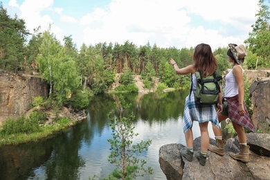 Photo of Young friends on rocky mountain in forest. Camping season