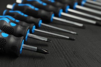 Photo of Set of screwdrivers on black wooden table, closeup