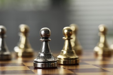 Golden and silver pawns on chess board, closeup