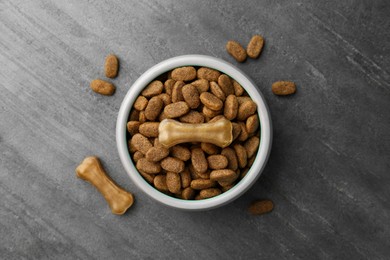 Dry dog food and treats (chew bones) on textured background, flat lay