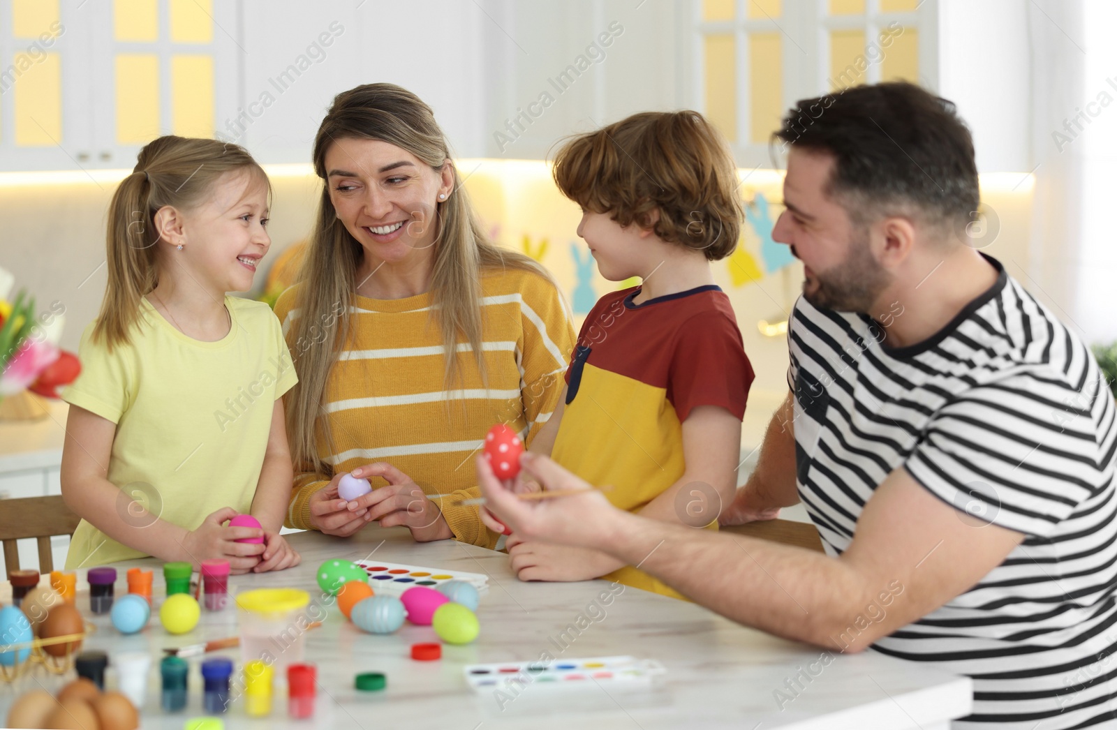 Photo of Happy Easter. Cute family with painted eggs at white marble table in kitchen