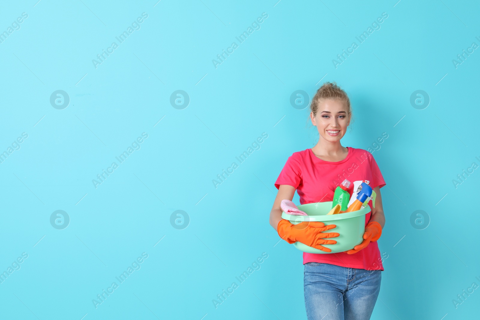 Photo of Woman with cleaning supplies on color background