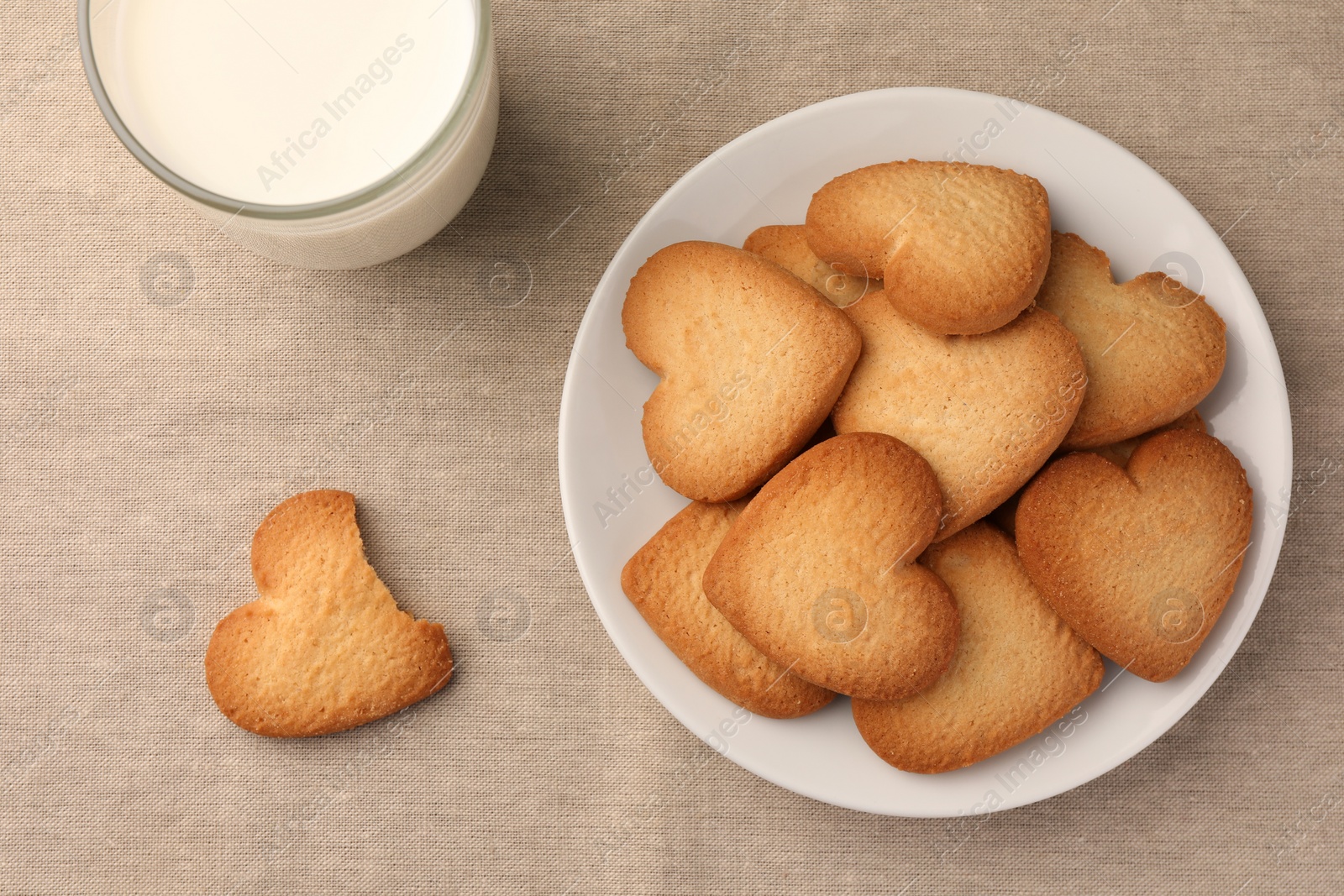 Photo of Heart shaped Danish butter cookies and milk on table, flat lay