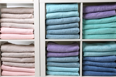 Photo of Colorful towels on shelves, closeup. Bathroom supplies