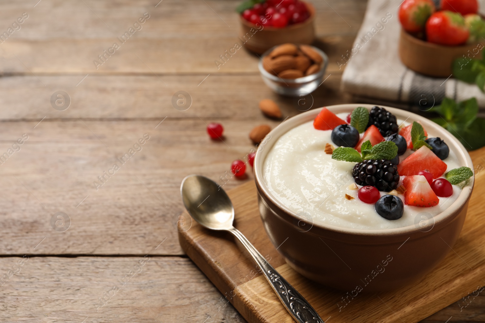 Photo of Delicious semolina pudding with berries on wooden table, space for text