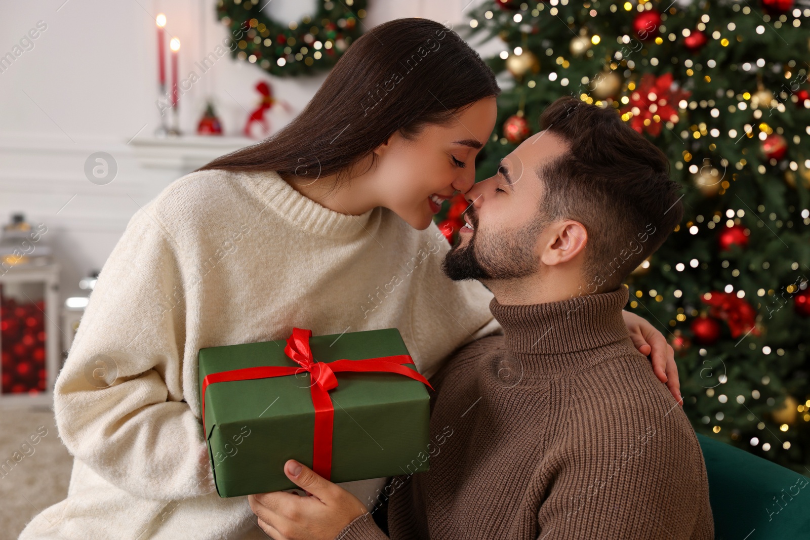 Photo of Beautiful young couple with Christmas gift at home