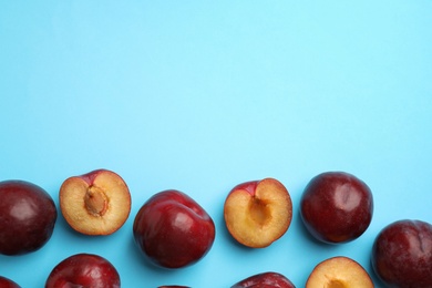 Photo of Delicious ripe plums on light blue background, flat lay. Space for text