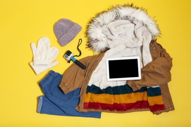 Set of warm clothes and devices on color background, flat lay. Winter vacation