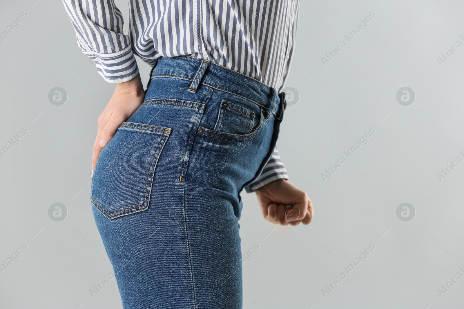 Photo of Woman suffering from hemorrhoid on light grey background, closeup