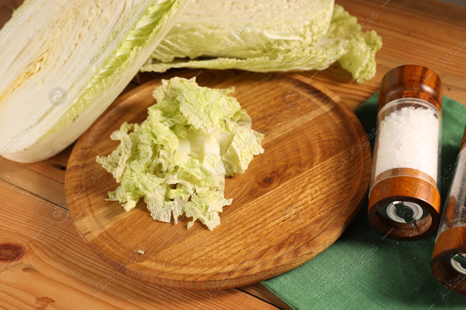 Photo of Fresh Chinese cabbage and salt on wooden table, closeup