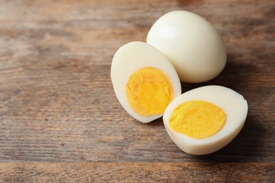 Photo of Hard boiled eggs on wooden table. Space for text