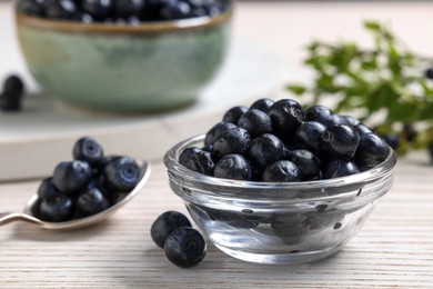 Photo of Ripe bilberries on white wooden table, closeup