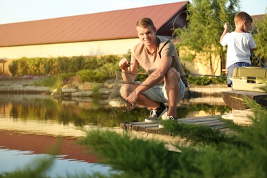 Dad and son fishing together on sunny day. Space for text