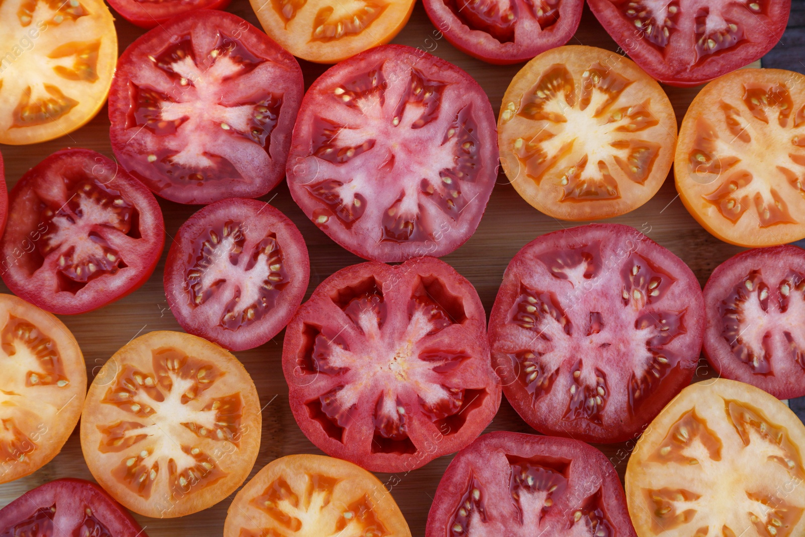 Photo of Cut tomatoes of different sorts on wooden table, flat lay