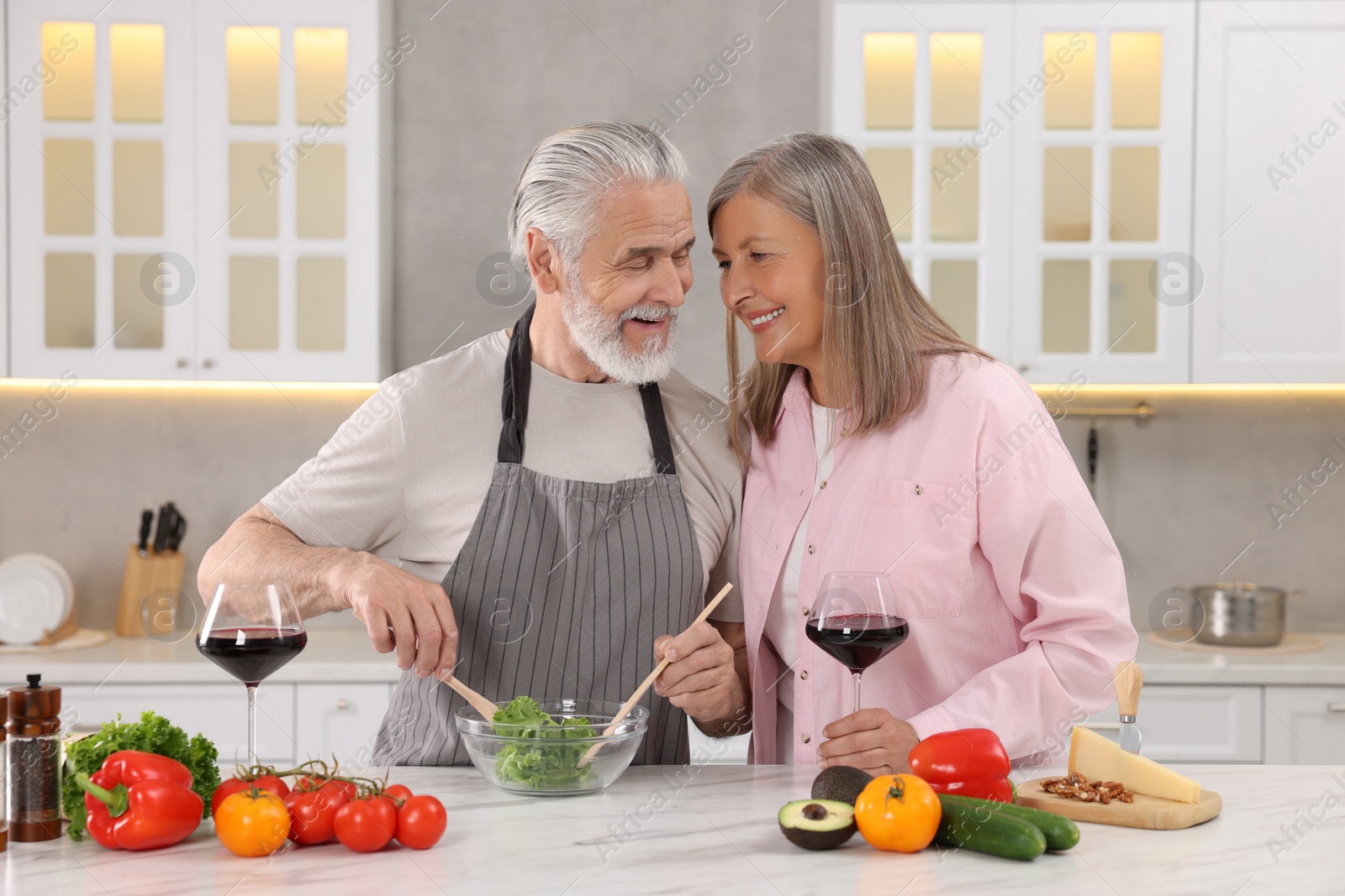 Photo of Affectionate senior couple cooking together in kitchen