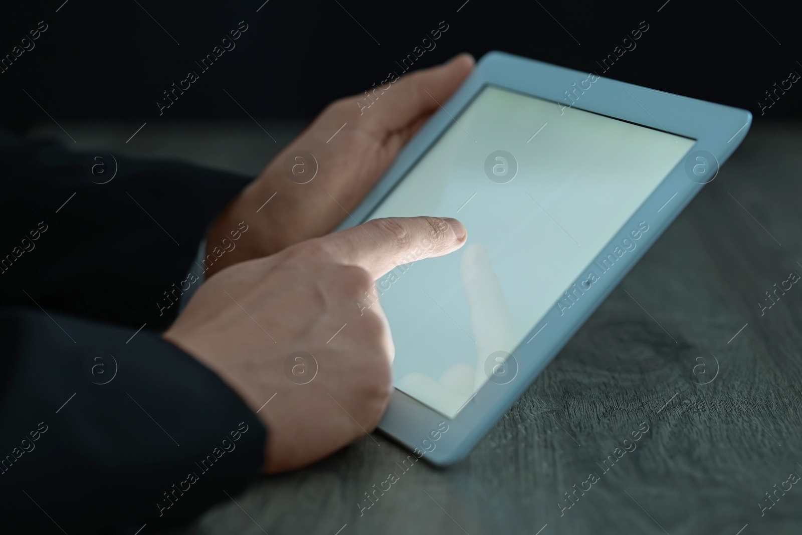 Photo of Man using tablet at wooden table, closeup view