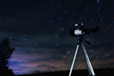 Photo of Modern telescope and beautiful sky in night outdoors. Star trail