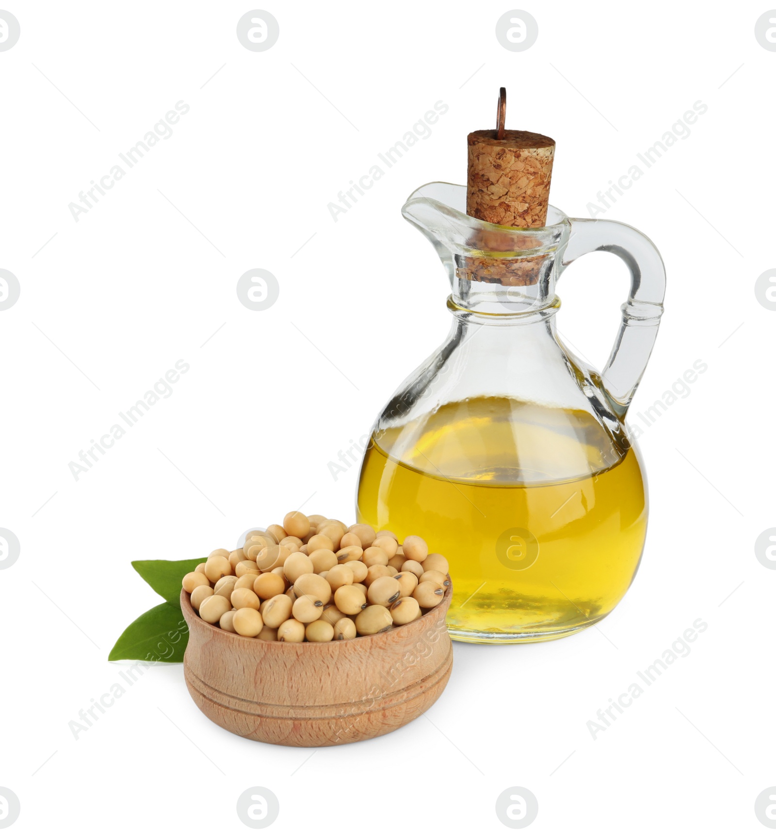 Photo of Glass jug of oil, soybeans and leaves on white background