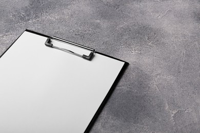 New clipboard with sheet of blank paper on grey textured table. Space for text