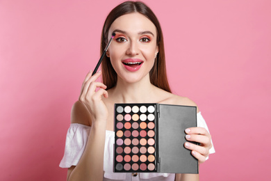 Photo of Beauty blogger applying eyeshadow on pink background