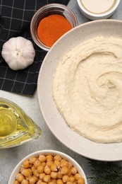 Photo of Bowl with delicious hummus and different ingredients on light grey table, flat lay