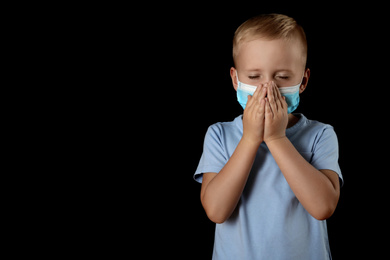 Photo of Little boy in medical mask on black background, space for text. Virus protection