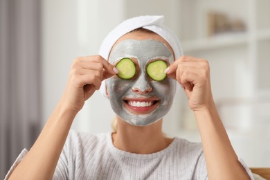 Photo of Young woman with face mask and cucumber slices at home. Spa treatments