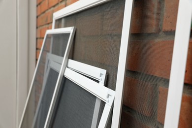 Set of window screens near brick wall indoors