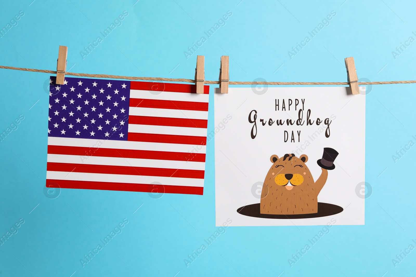 Photo of Happy Groundhog Day greeting card and American flag hanging on light blue background