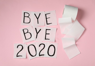 Photo of Toilet paper with text Bye Bye 2020 on pink background, flat lay