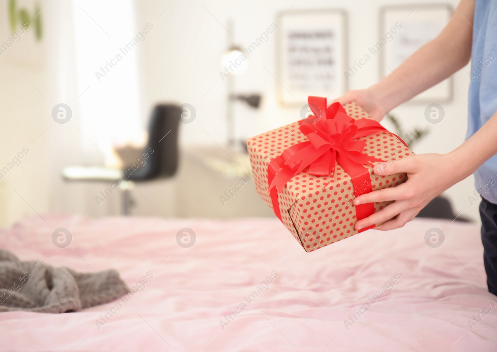 Photo of Little child putting gift box for Mother's Day on bed