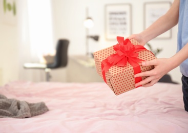 Photo of Little child putting gift box for Mother's Day on bed