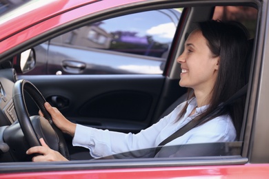 Woman with fastened safety belt on driver's seat in car