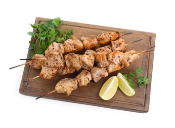 Photo of Wooden board with delicious fresh shish kebabs, parsley and lemon isolated on white, top view