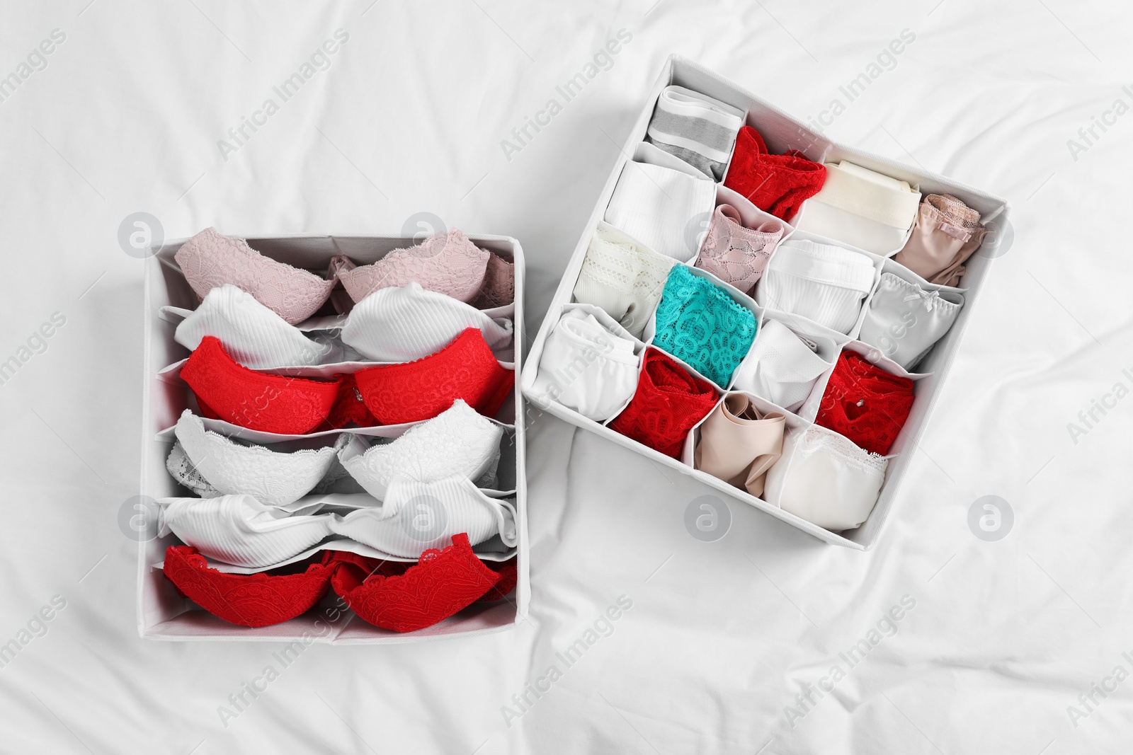 Photo of Organizers with stylish women's underwear on bed, flat lay