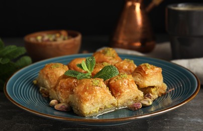 Delicious baklava with pistachio nuts and mint on grey table