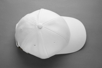 Photo of Stylish white baseball cap on grey background, top view