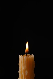 Burning church wax candle on black background