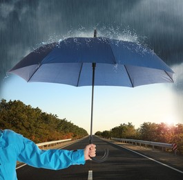 Image of Woman with open blue umbrella on empty asphalt road, closeup