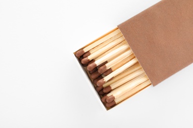 Photo of Cardboard box with matches on white background, top view. Space for design