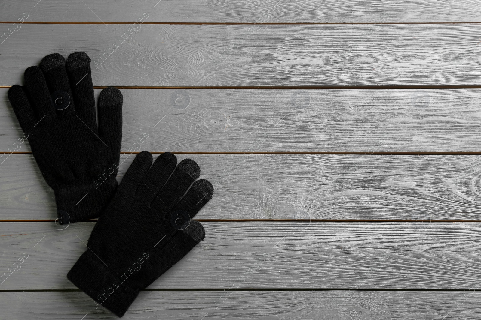 Photo of Stylish black gloves on grey wooden background, flat lay. Space for text