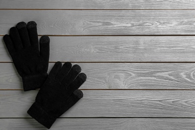 Stylish black gloves on grey wooden background, flat lay. Space for text