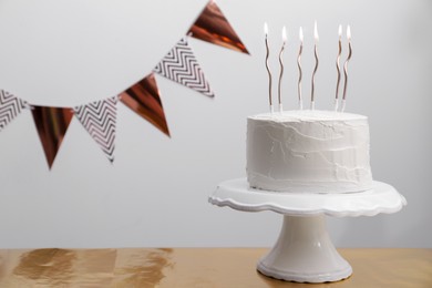 Delicious cake with cream and burning candles on wooden table. Space for text