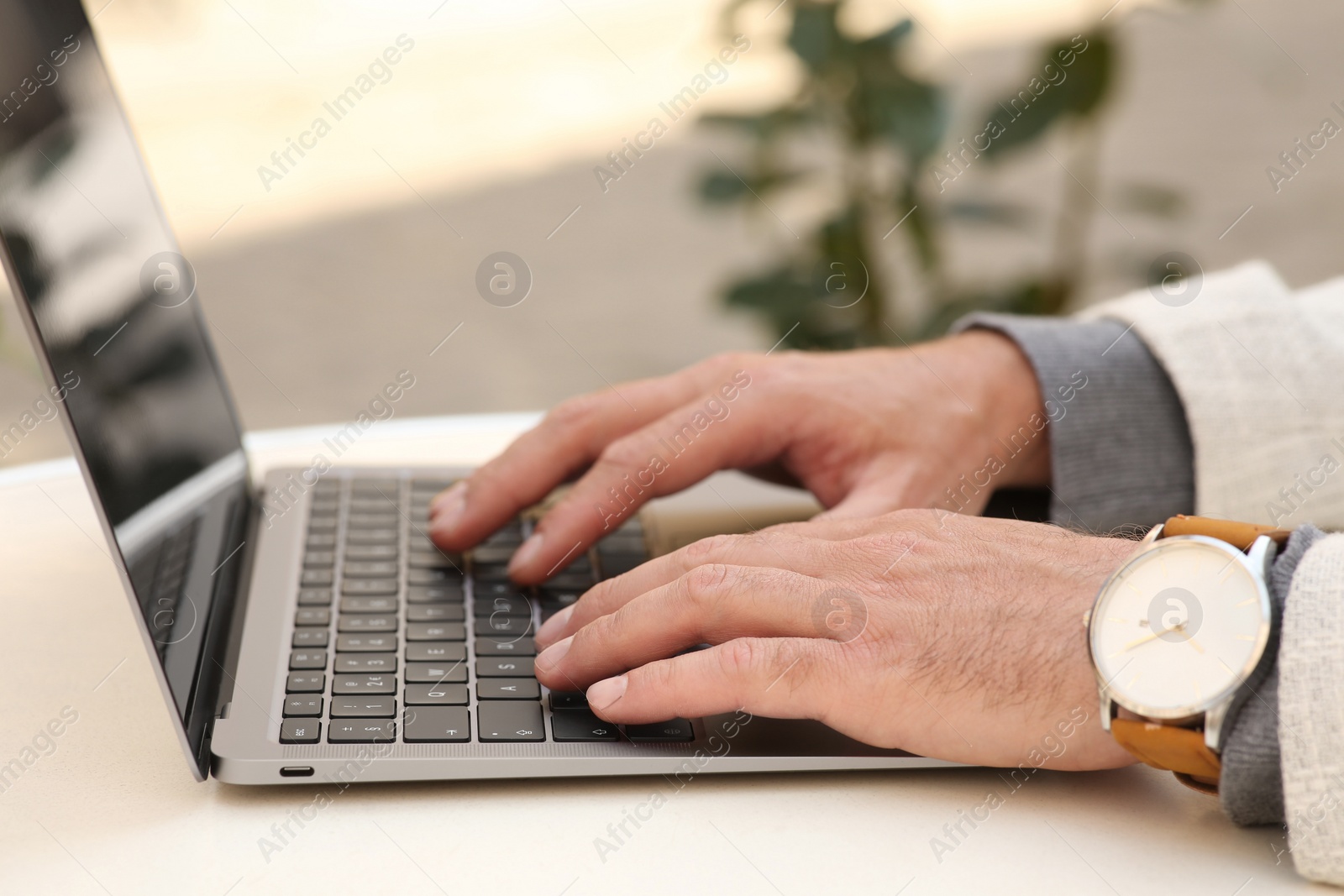 Photo of Man working on laptop at table in cafe, closeup